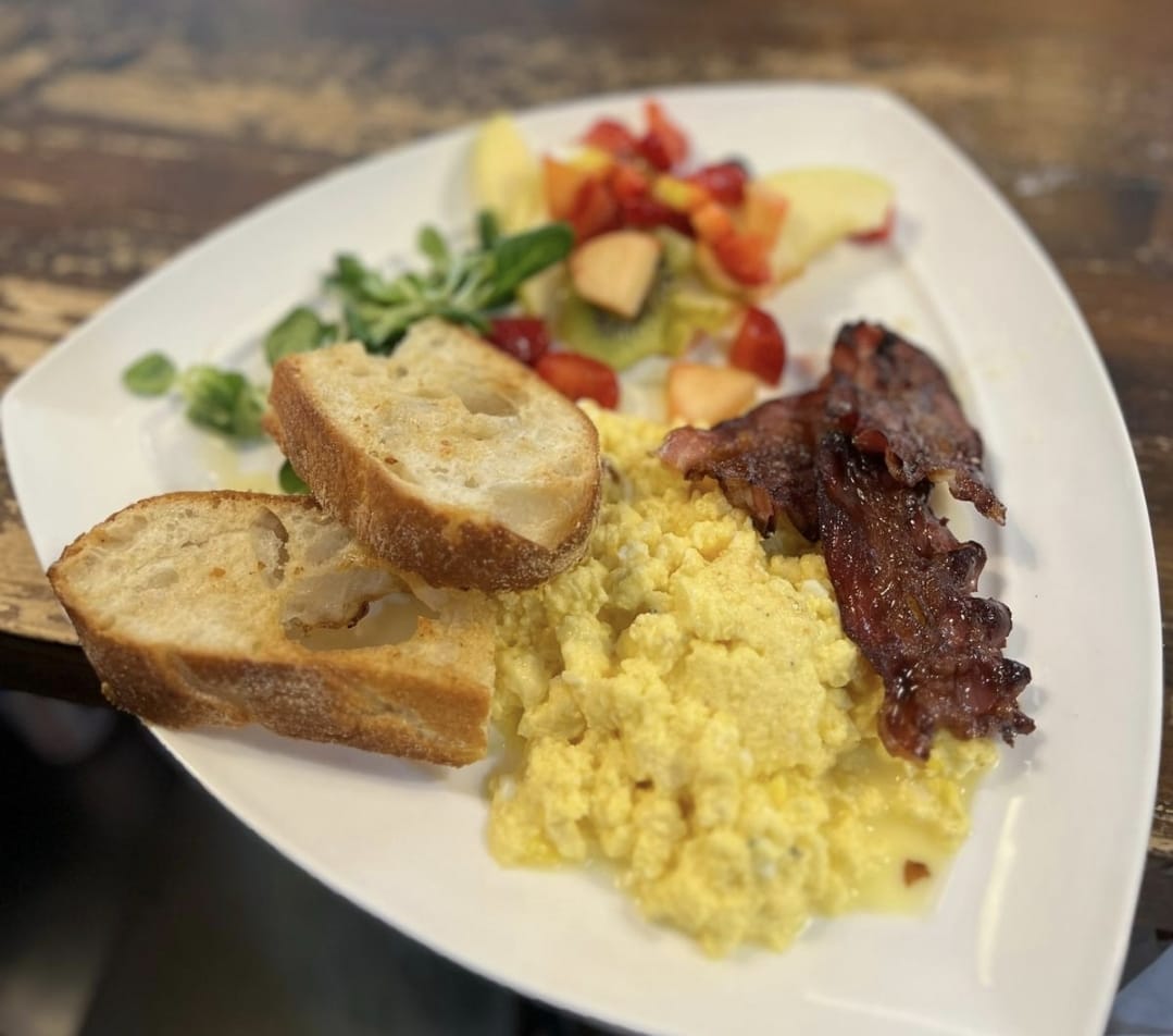 English breakfast con uova strapazzate, bacon e frutta fresca
